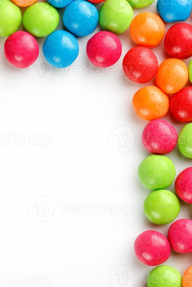 A rainbow of color from multicolored candies close-up, multi-colored glaze dragee on a white background photo