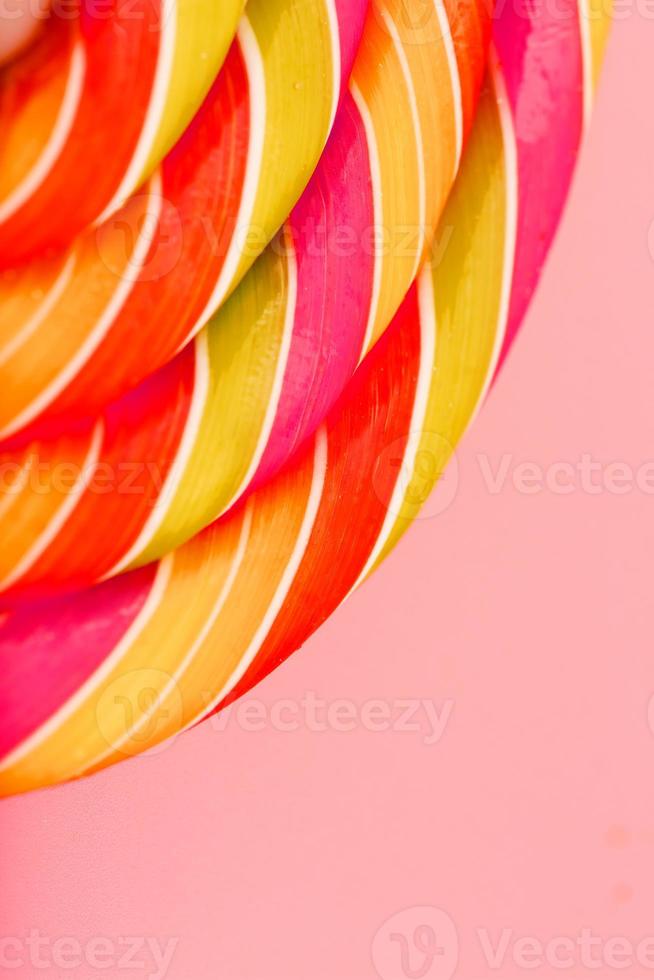 Lollipop multicolored close-up as background texture on pieces on pink background. photo