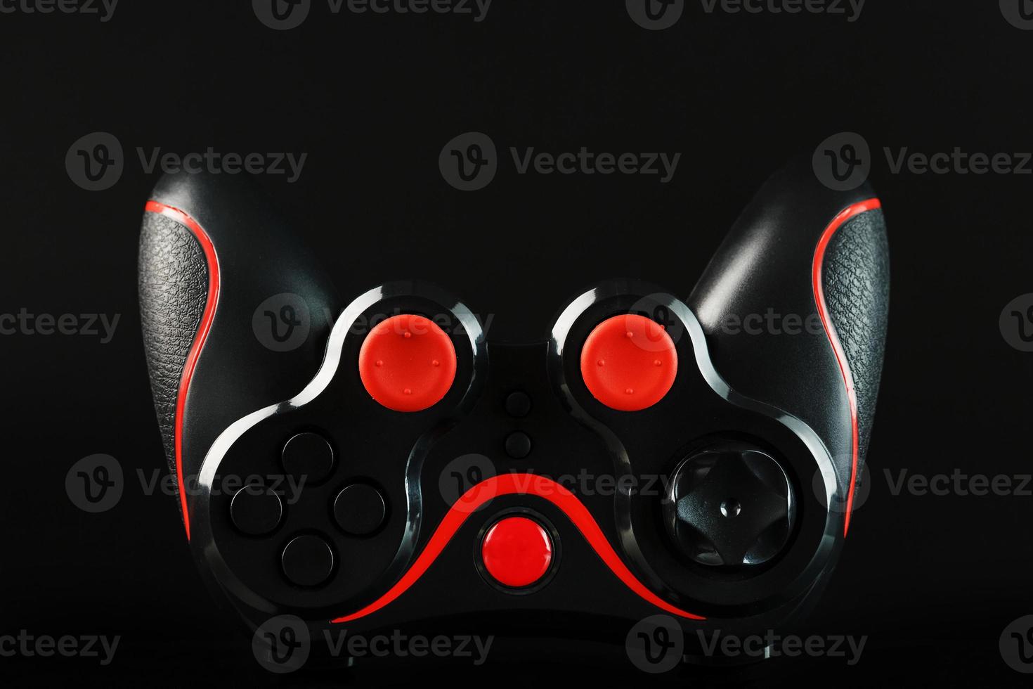controlador de juego negro gamepad con botones rojos sobre fondo negro al revés de cerca foto