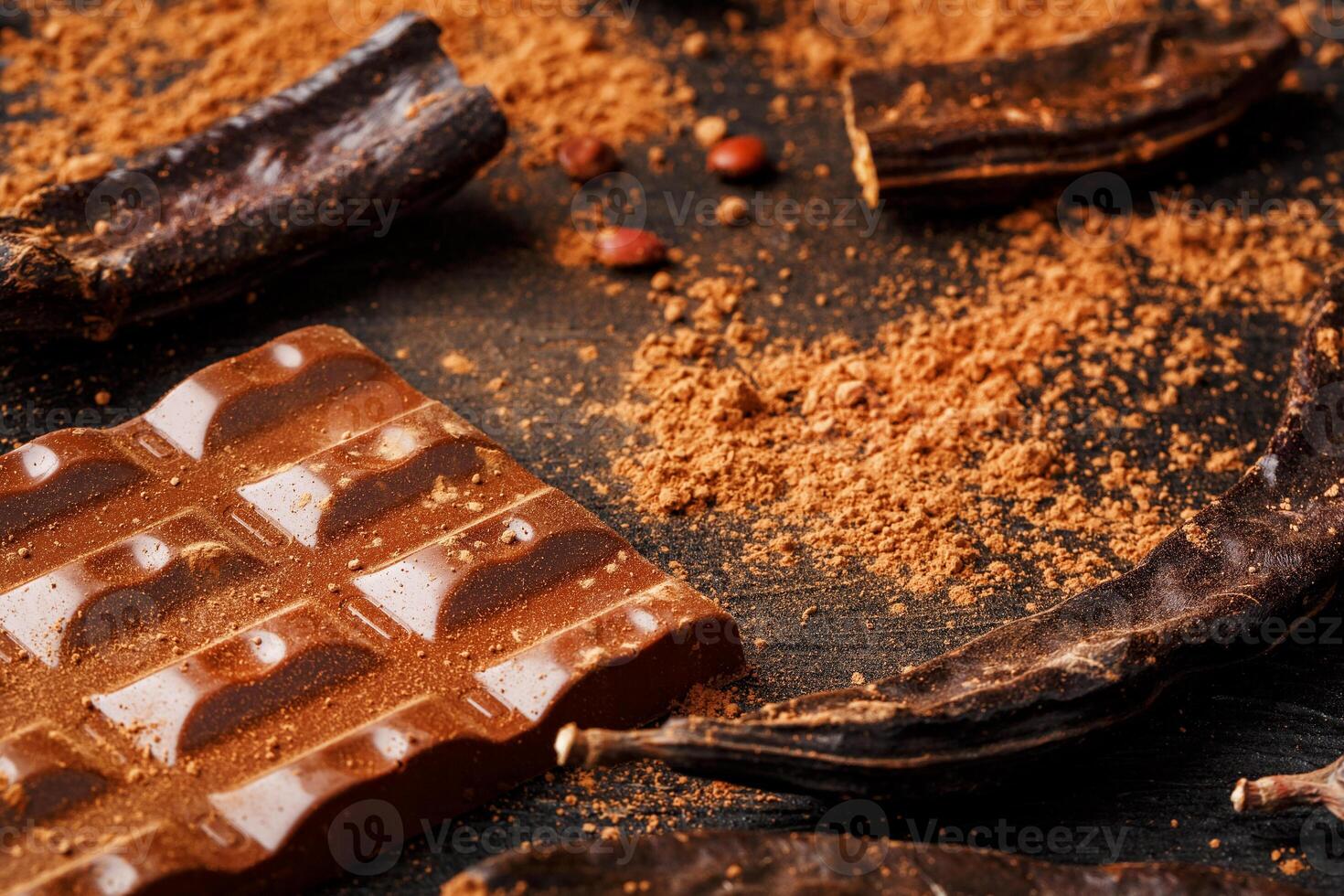Carob chocolate and carob fruit powder on dark background. A tasty and