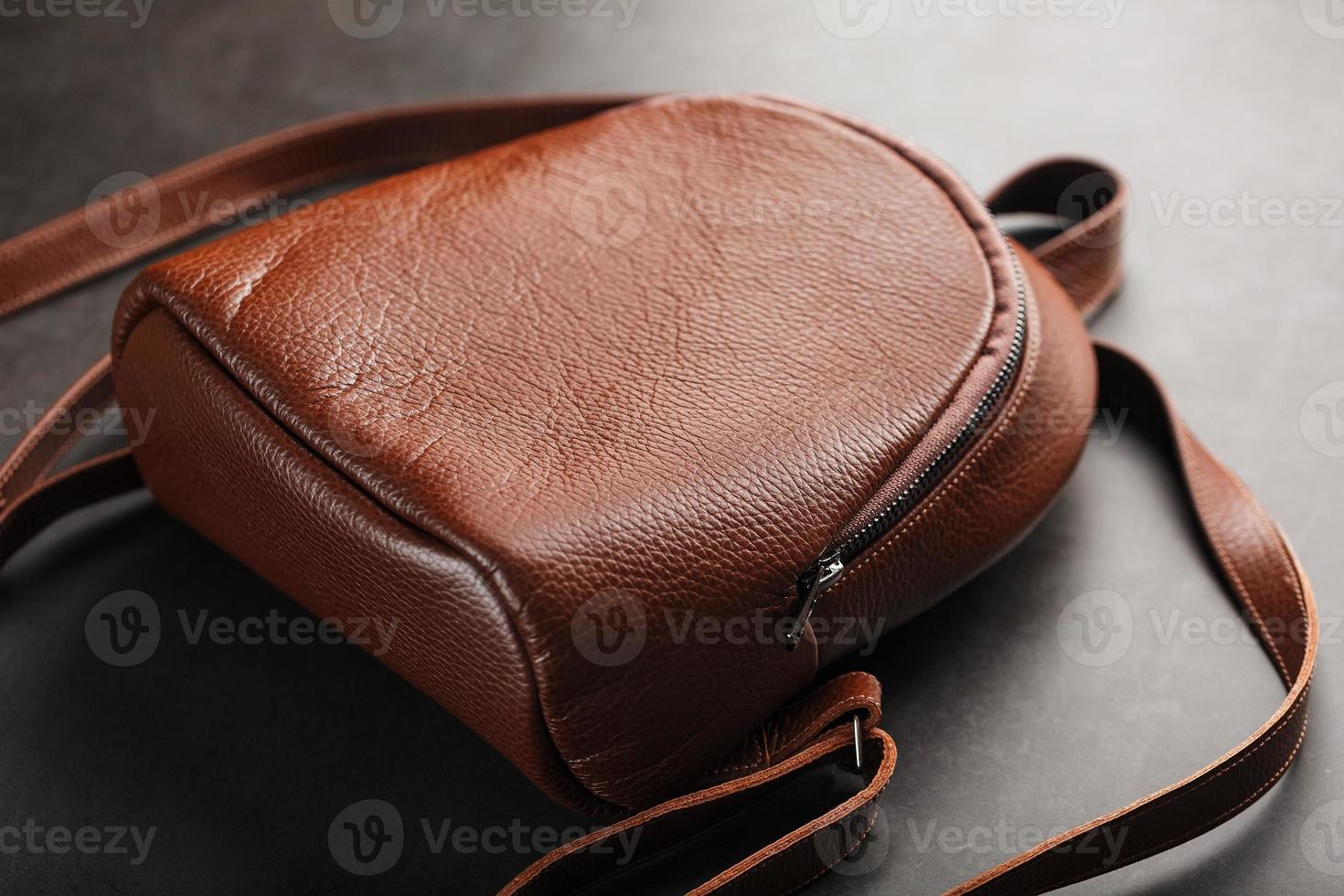 Brown backpack made of textured brown leather on a black stone background. Elegant golden brown women backpack with fashion and rivets photo