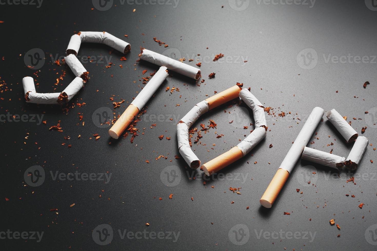 The inscription STOP from cigarettes on a black background. Stop smoking. The concept of smoking kills. Motivation inscription to quit smoking, unhealthy habit. photo