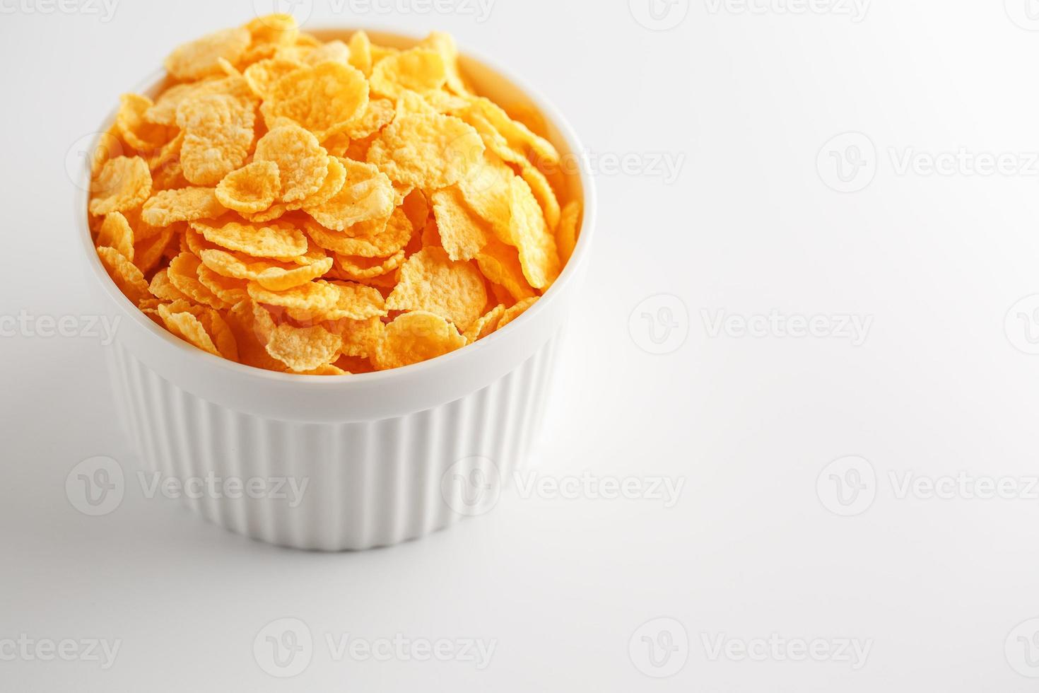 White cup with golden corn flakes isolated on white background. View from above. Delicious and healthy breakfast photo