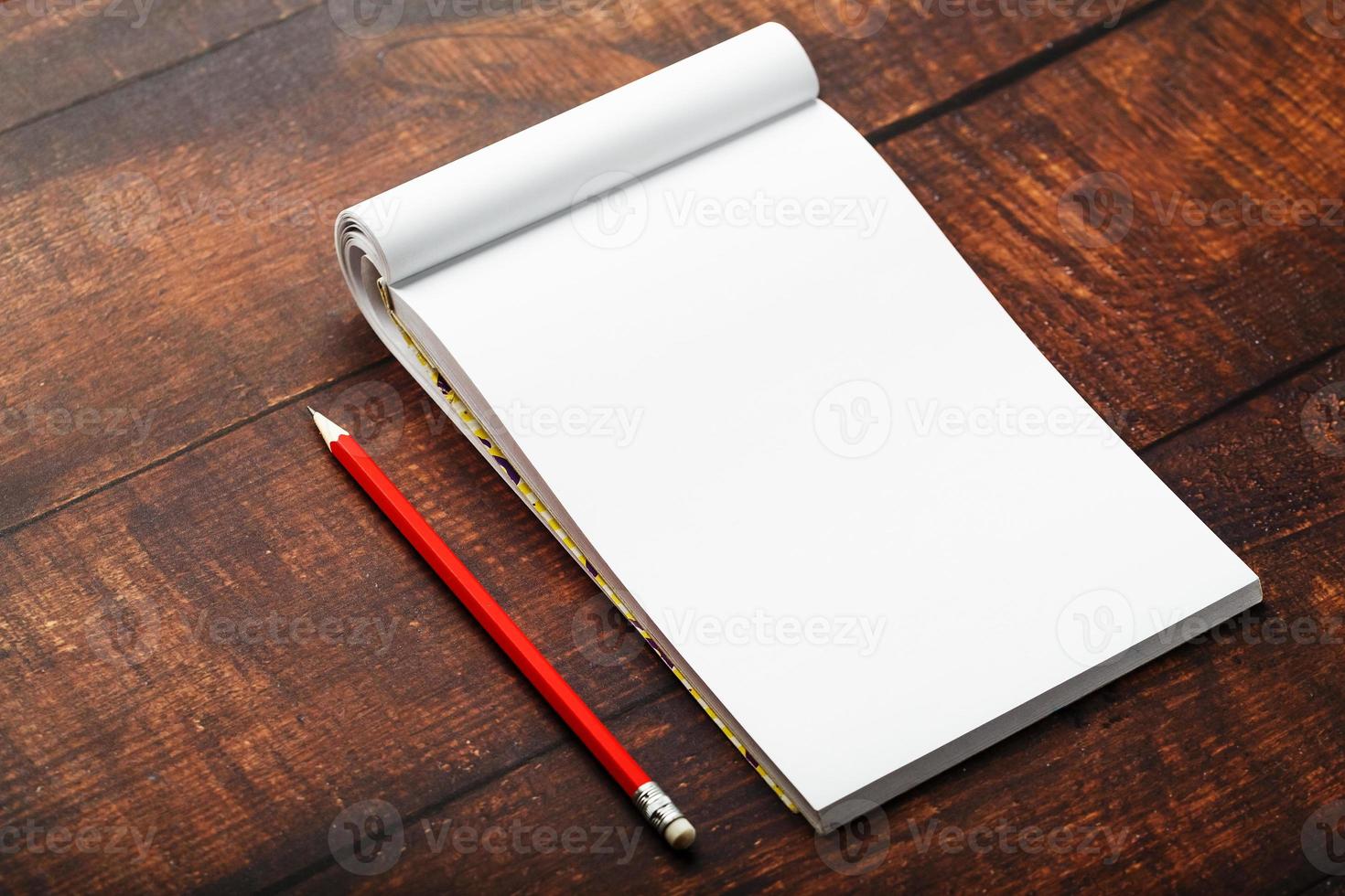 Notepad with red pencil on a brown wooden table background, for education, write goals and deeds photo