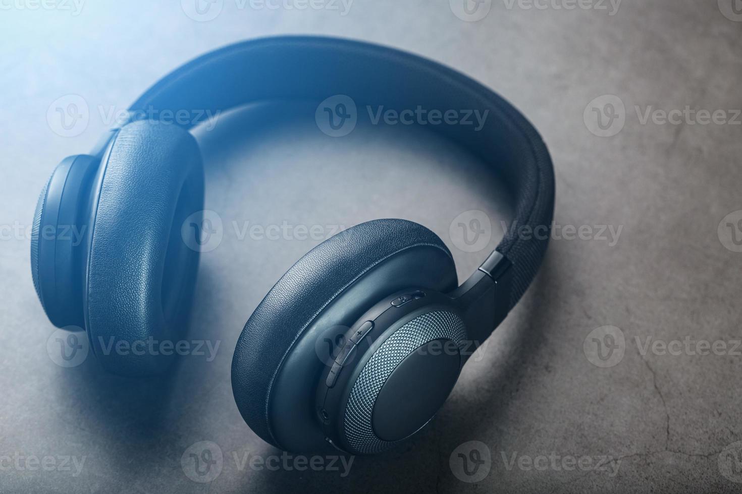 Black Wireless headphones on a black, stone background with a godly flare of blue and gold. Overhead, isolated professional-grade headphones for DJs and musicians. photo