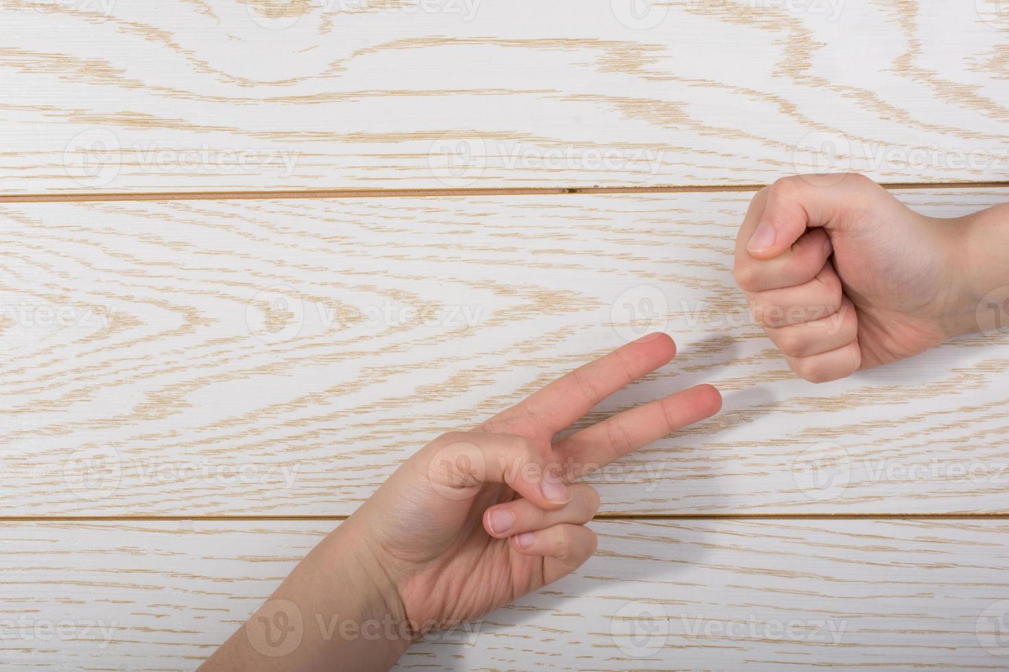 Hands making rock, paper, scissors gesture on wooden background photo