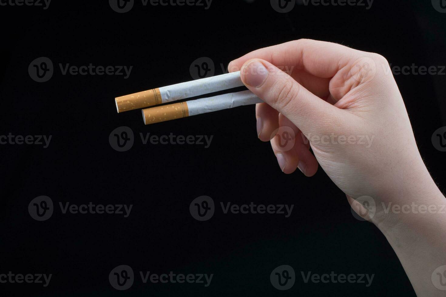 mano sostiene cigarrillos sobre fondo negro foto
