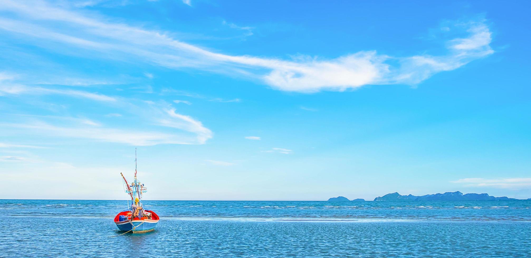 una vista de un barco de pesca amarrado por el mar en la mañana con un hermoso cielo y mar azul. foto