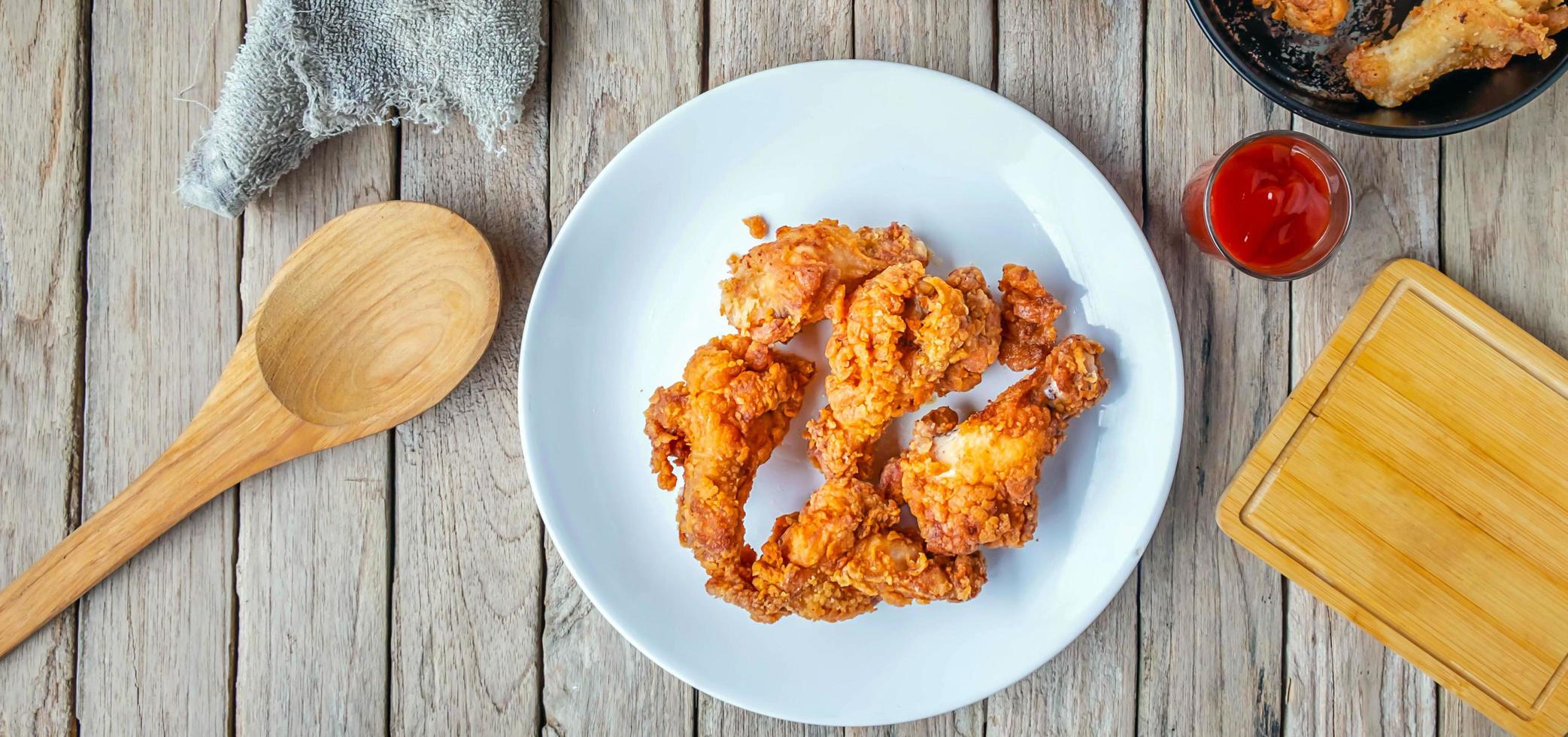 Top view of Fried chicken food and Fried Chicken Drumsticks wite french fries and tomato ketchup on a wooden table photo