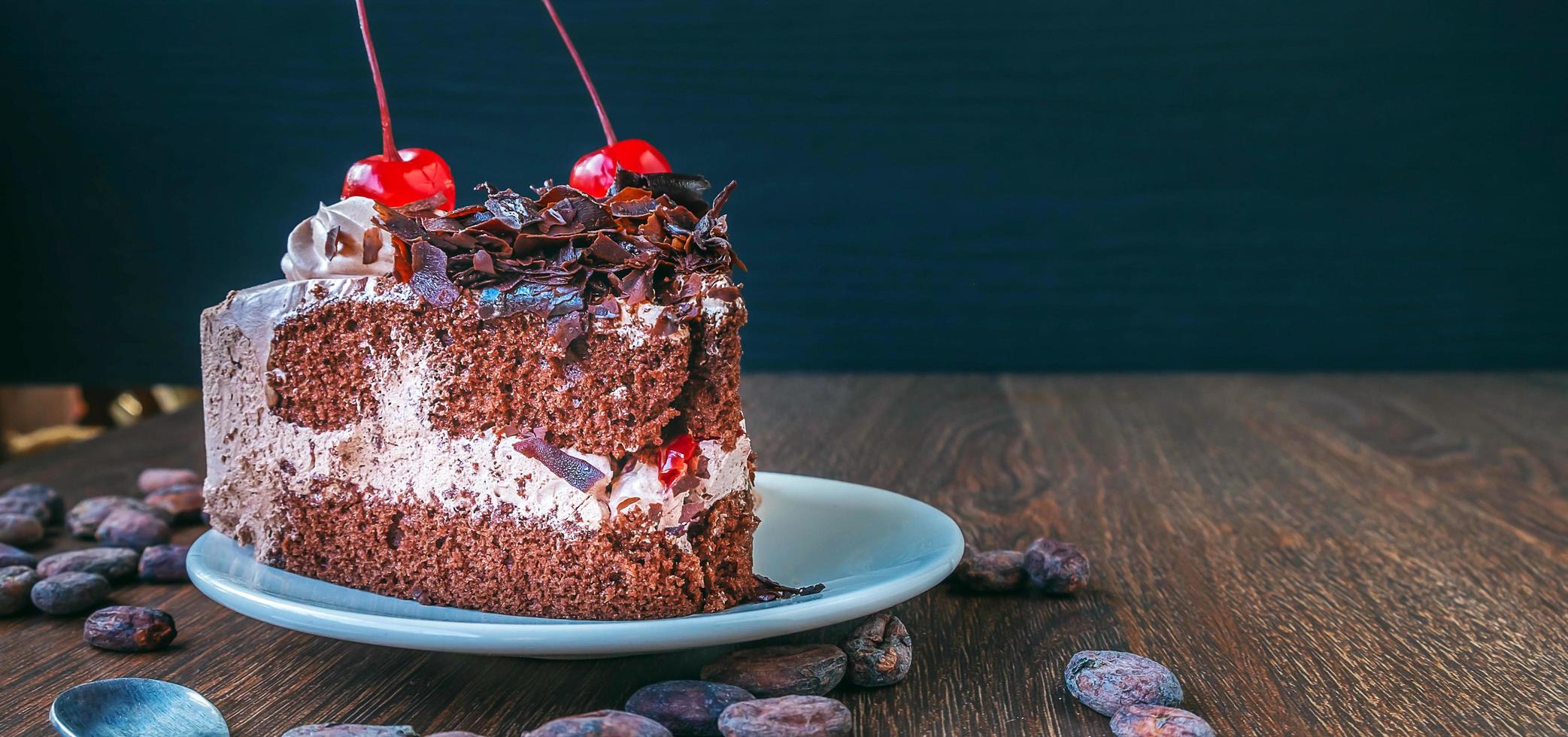 Slice of chocolate cheesecake on plate and cocoa beans on wooden table, above view over a rustic  wood background photo