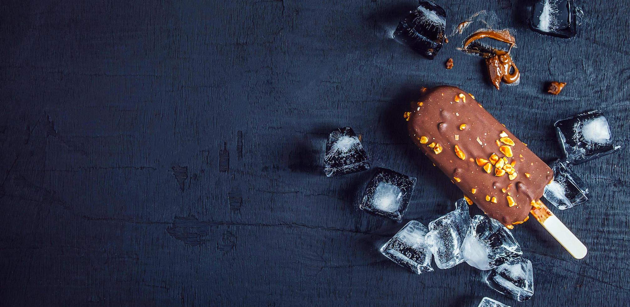 una deliciosa barra de helado de chocolate con almendras y cubitos de hielo se coloca sobre un fondo negro.vista superior foto