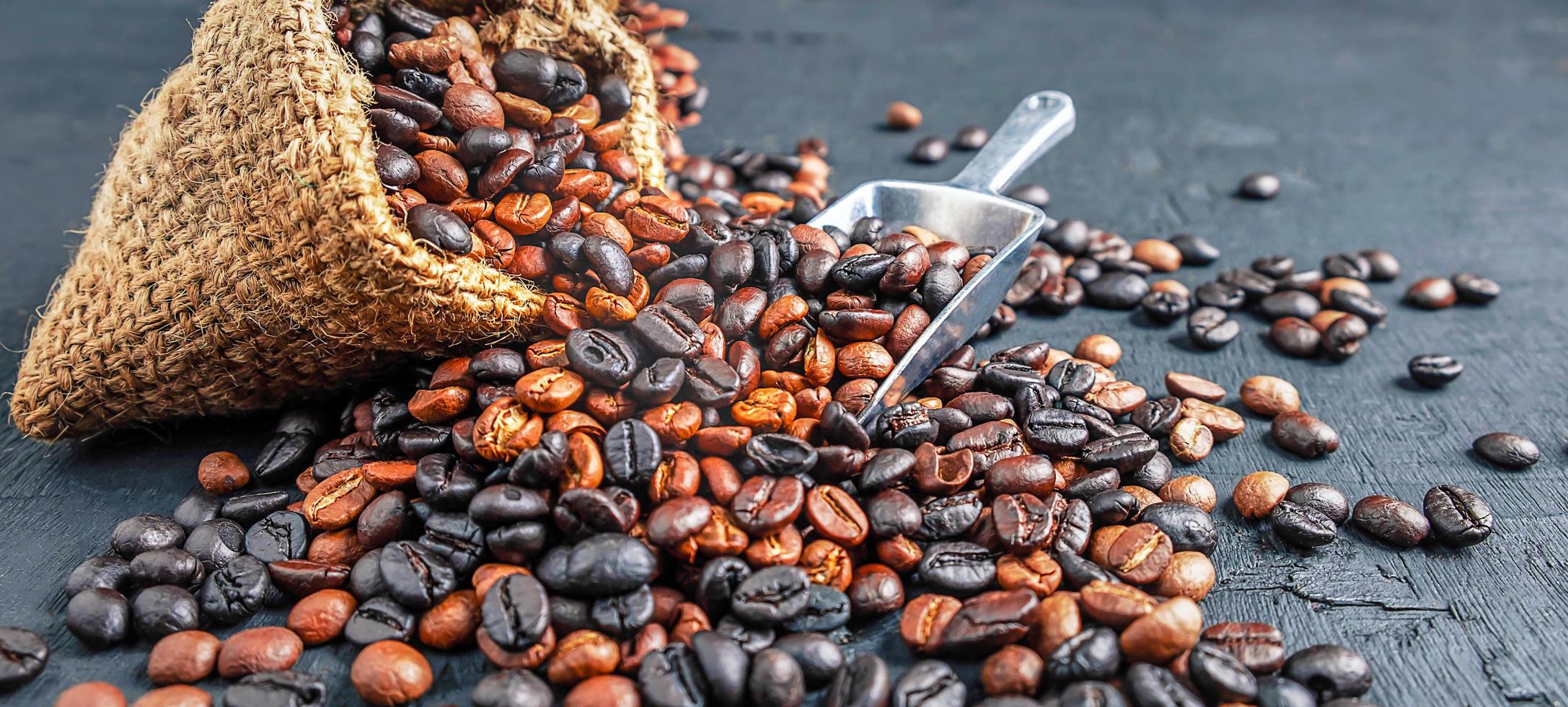 primer plano de una mezcla combinada de tueste oscuro y un tueste medio de granos de café tostados en una bolsa de saco marrón foto