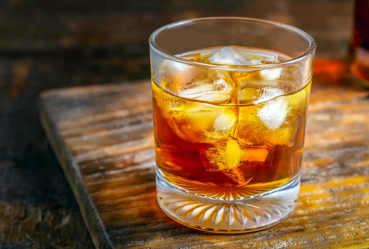 primer plano de un vaso de licor con cubitos de hielo en una mesa de madera foto