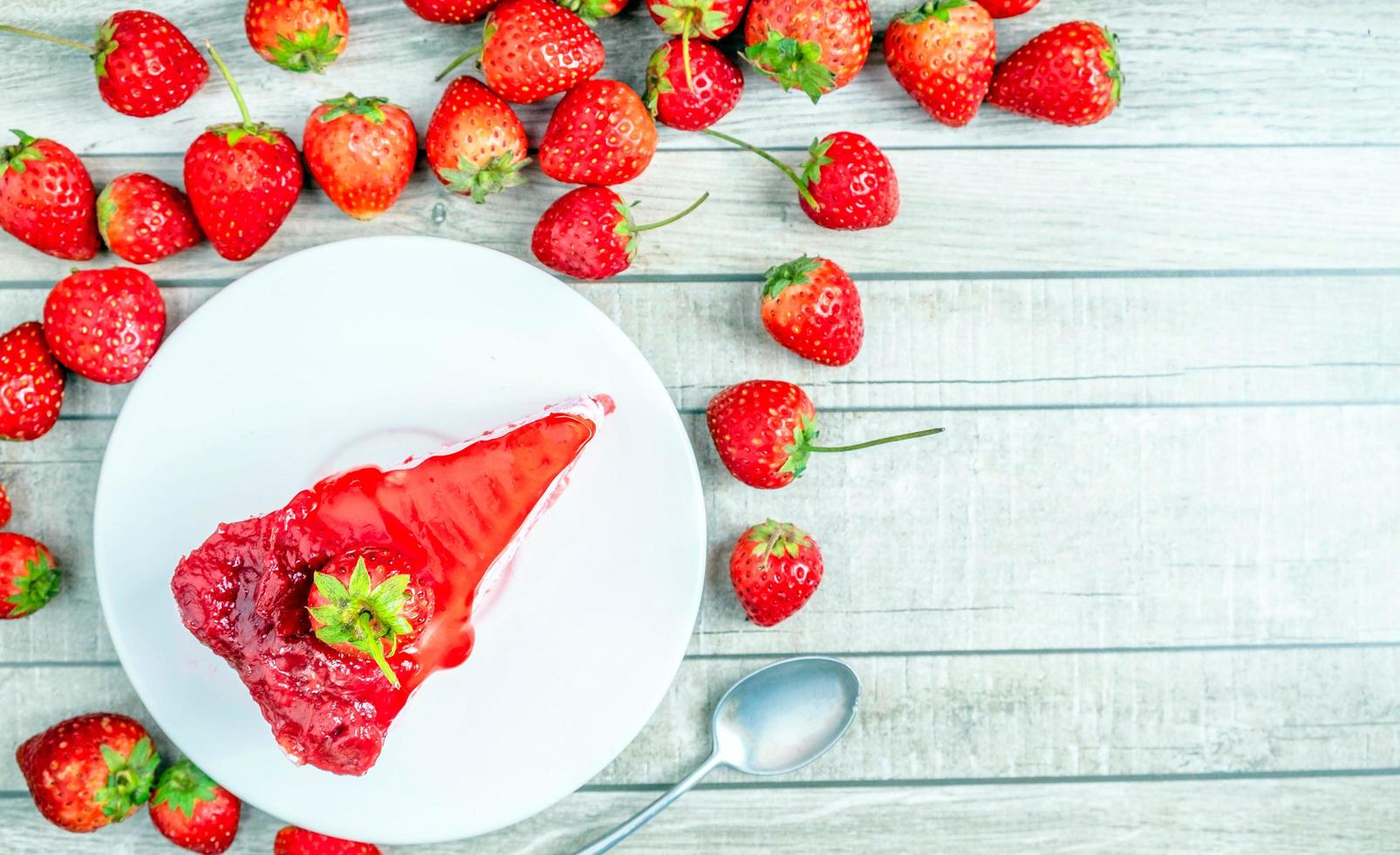 vista superior de rebanadas de pastel de fresa frescas en un plato y frutas de fresas rojas frescas sobre un fondo azul de madera vieja foto