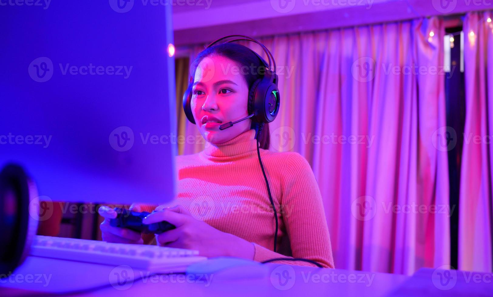 An active and serious young woman gamer on his powerful personal computer, playing first-person online video games. photo