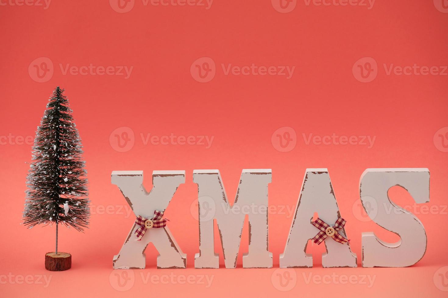 Wooden letters XMAS and decorative Christmas tree on pink background. Christmas greeting card photo