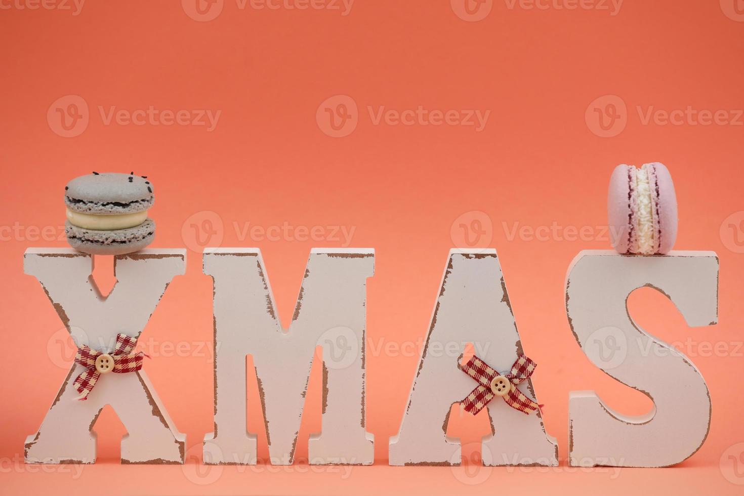 The wooden word xmas with colorful macaroons or macarons on pink background. Xmas decoration. New Year home decor photo