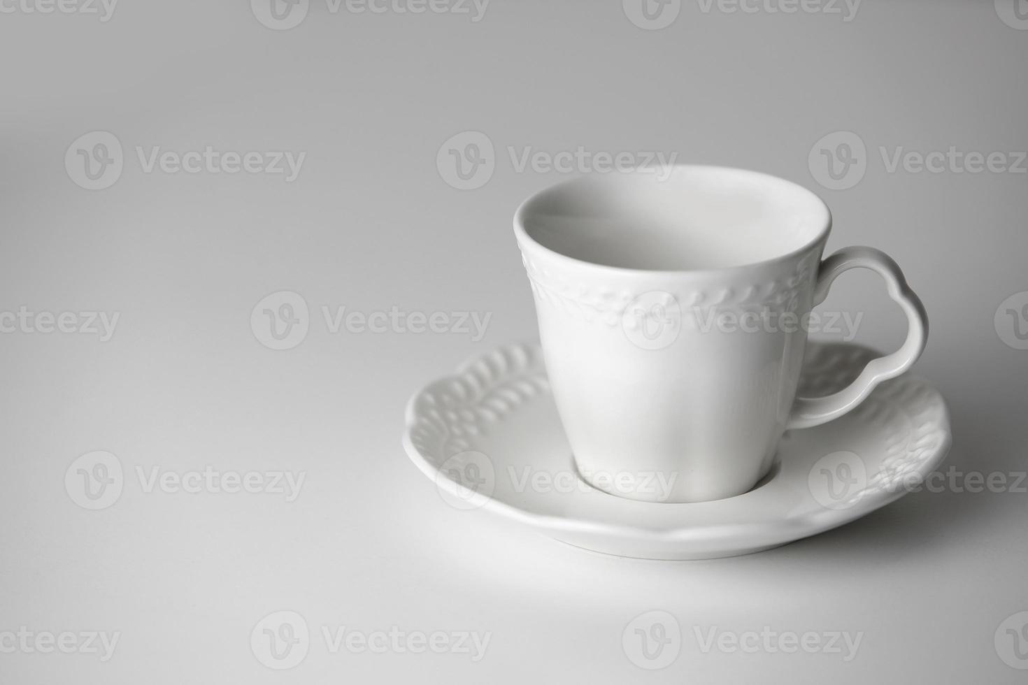 White tea cup and saucer with a pattern for drink on white background. Ceramic coffee cup or mug close up. Mockup classic porcelain utensils. copy space photo