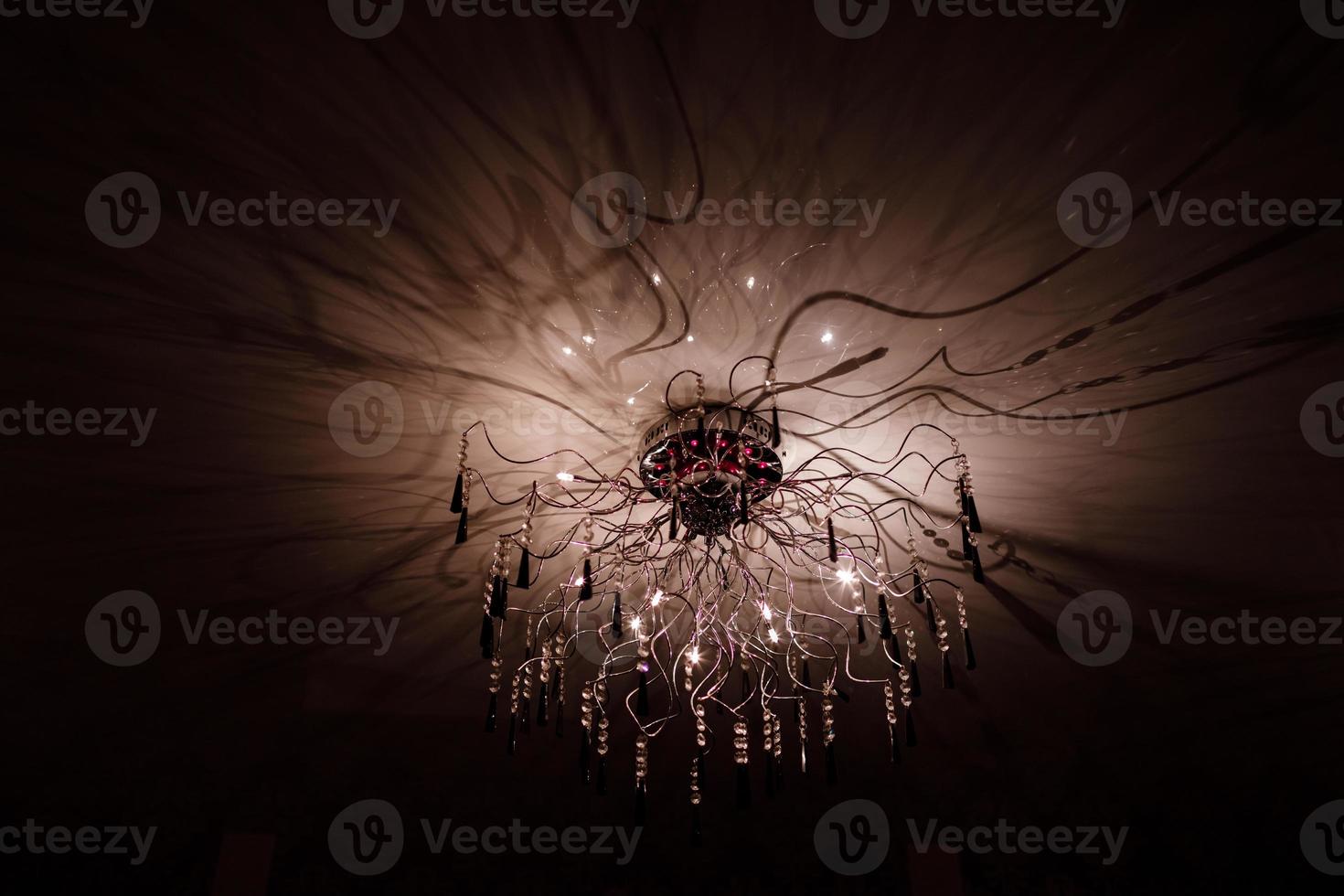 Chandelier.Home, beautiful chandelier.A luxurious lamp hangs from the ceiling. handelier with crystal.Chandelier ceiling lights, black background with copy space.Close Up. photo