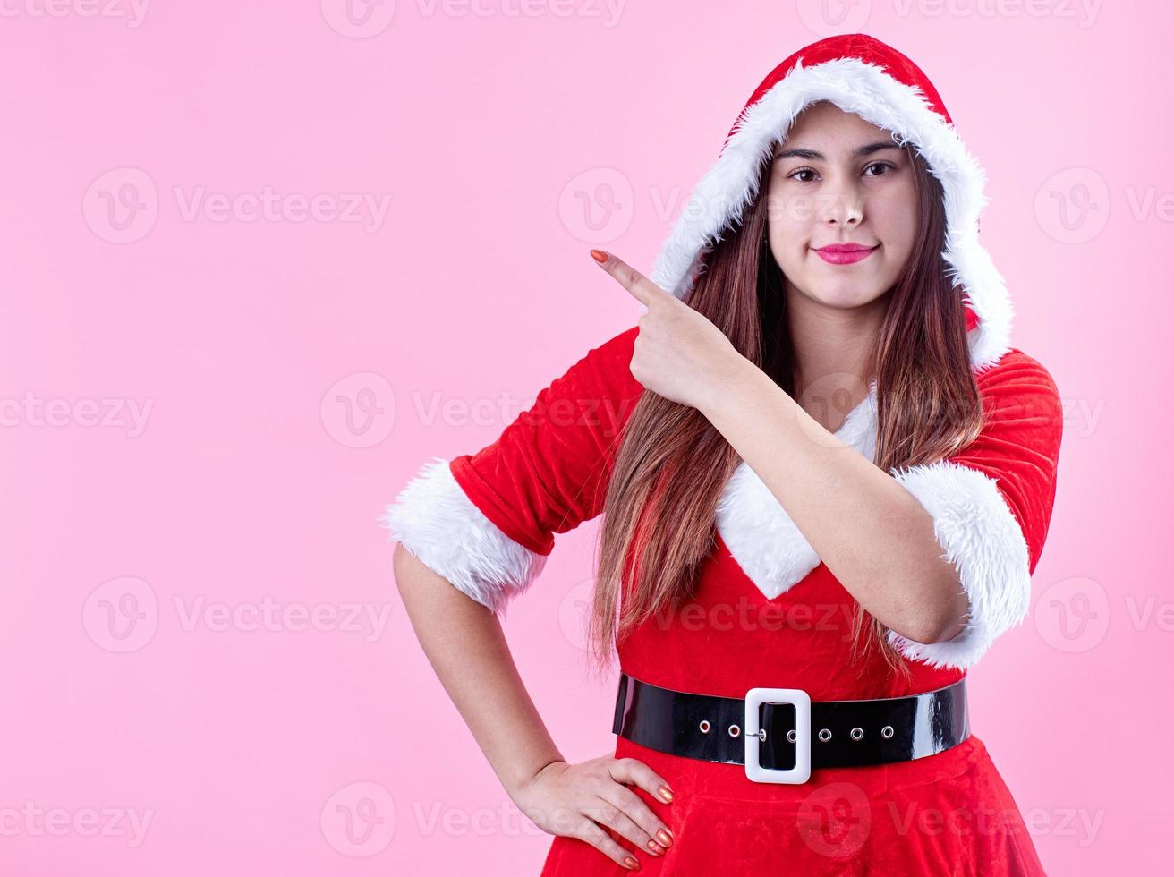 primer plano de una mujer caucásica feliz con ropa de santa sonriendo y señalando con el dedo foto