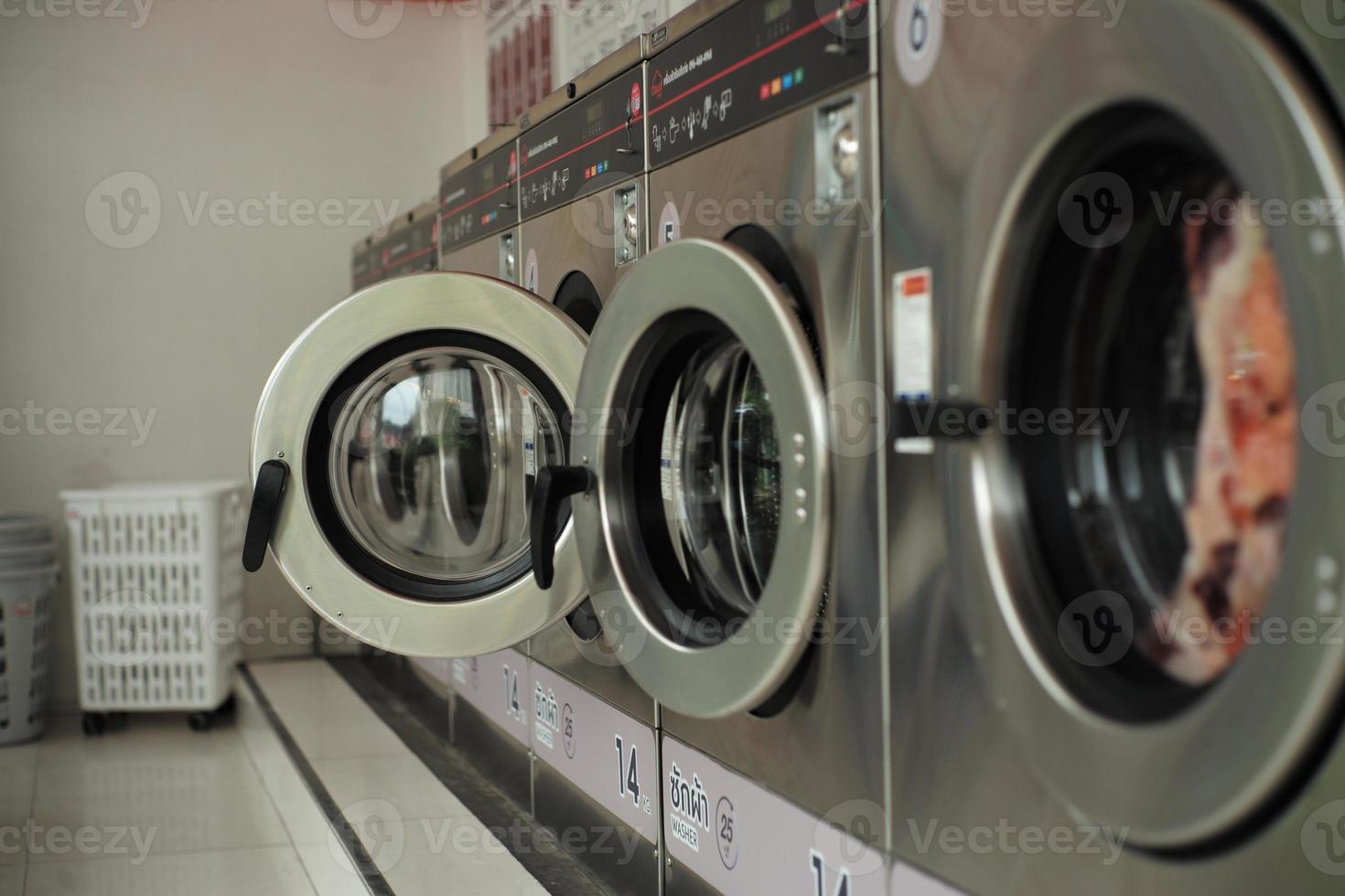 Selective focus on the front door of the washing machine with blurred close doors in foreground. Row of washing machines in the washing shop photo