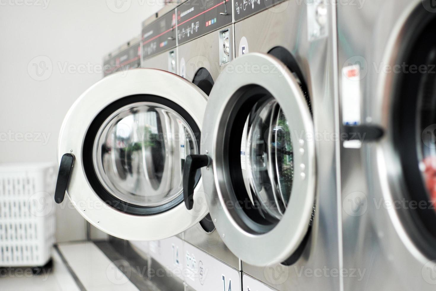 Selective focus on the front door of the washing machine with blurred close doors in foreground. Row of washing machines in the washing shop photo