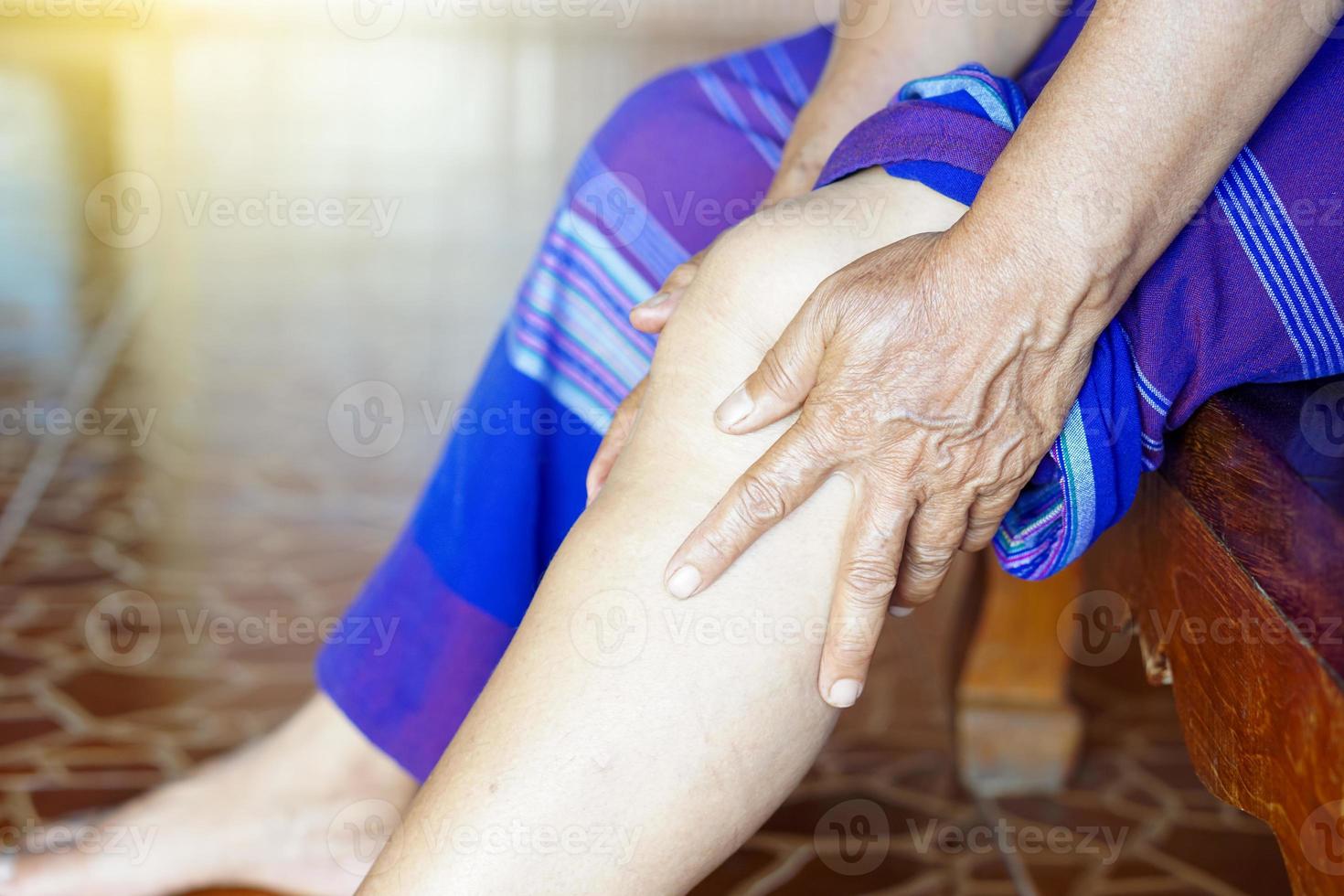 Las manos de una anciana de primer plano masajean su rodilla dolorosa. concepto, problemas de salud. lesión de rodilla, artrosis. hueso superpuesto. foto