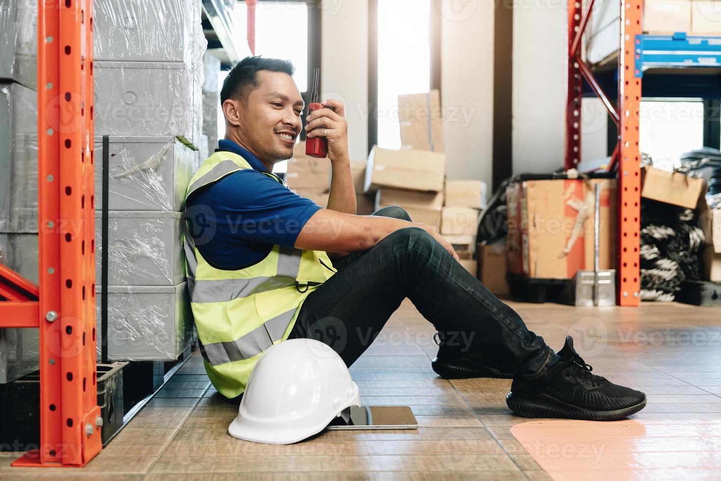 Asian male worker in safety uniform talking on walkie talkie to colleagues. engineer or driver working at logistic warehouse distribution center. shipping and delivery photo