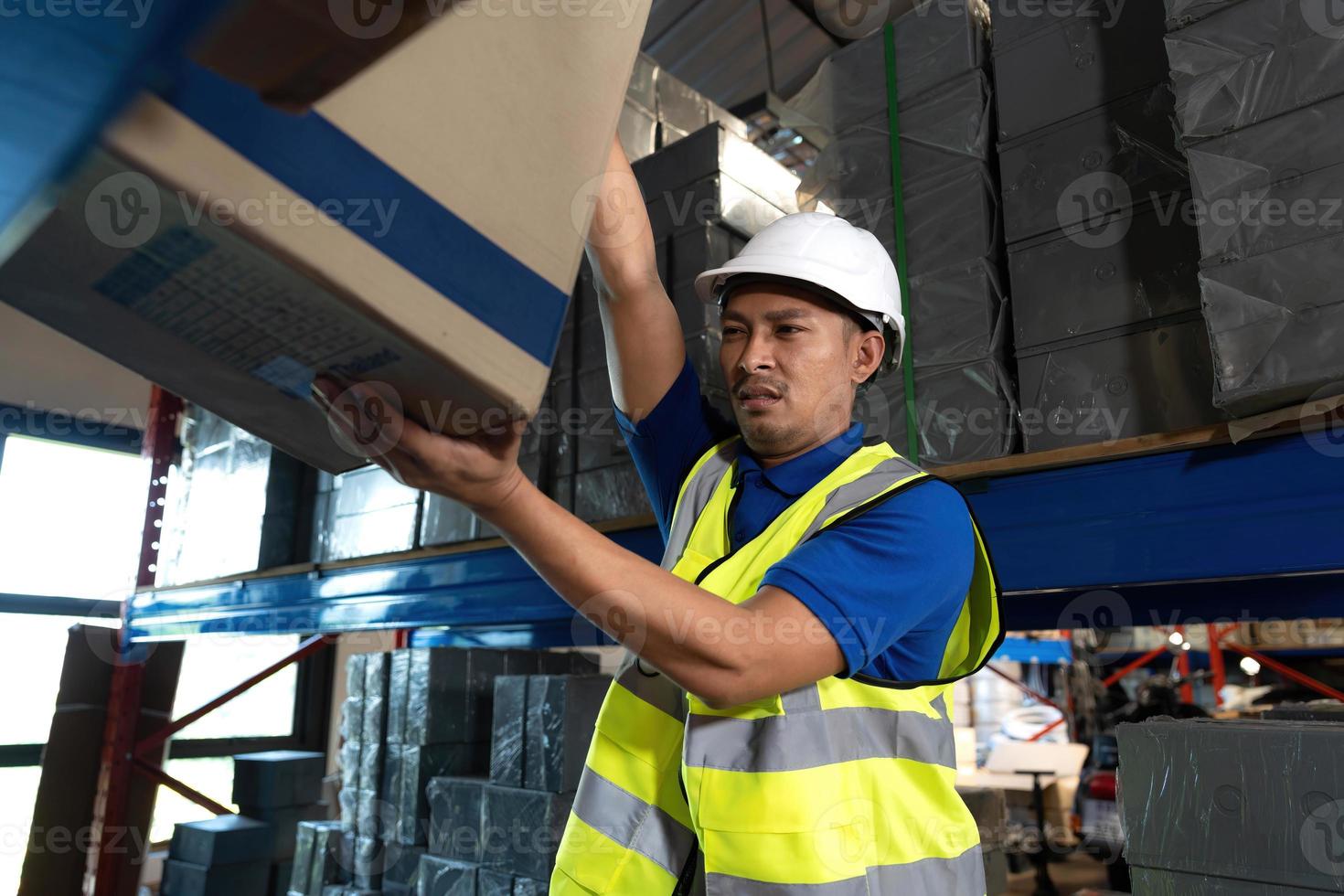 trabajador de almacén masculino asiático milenario inteligente en su uniforme trabajando en el almacén, revisando el inventario en el paquete. trabajo de almacén de envío foto