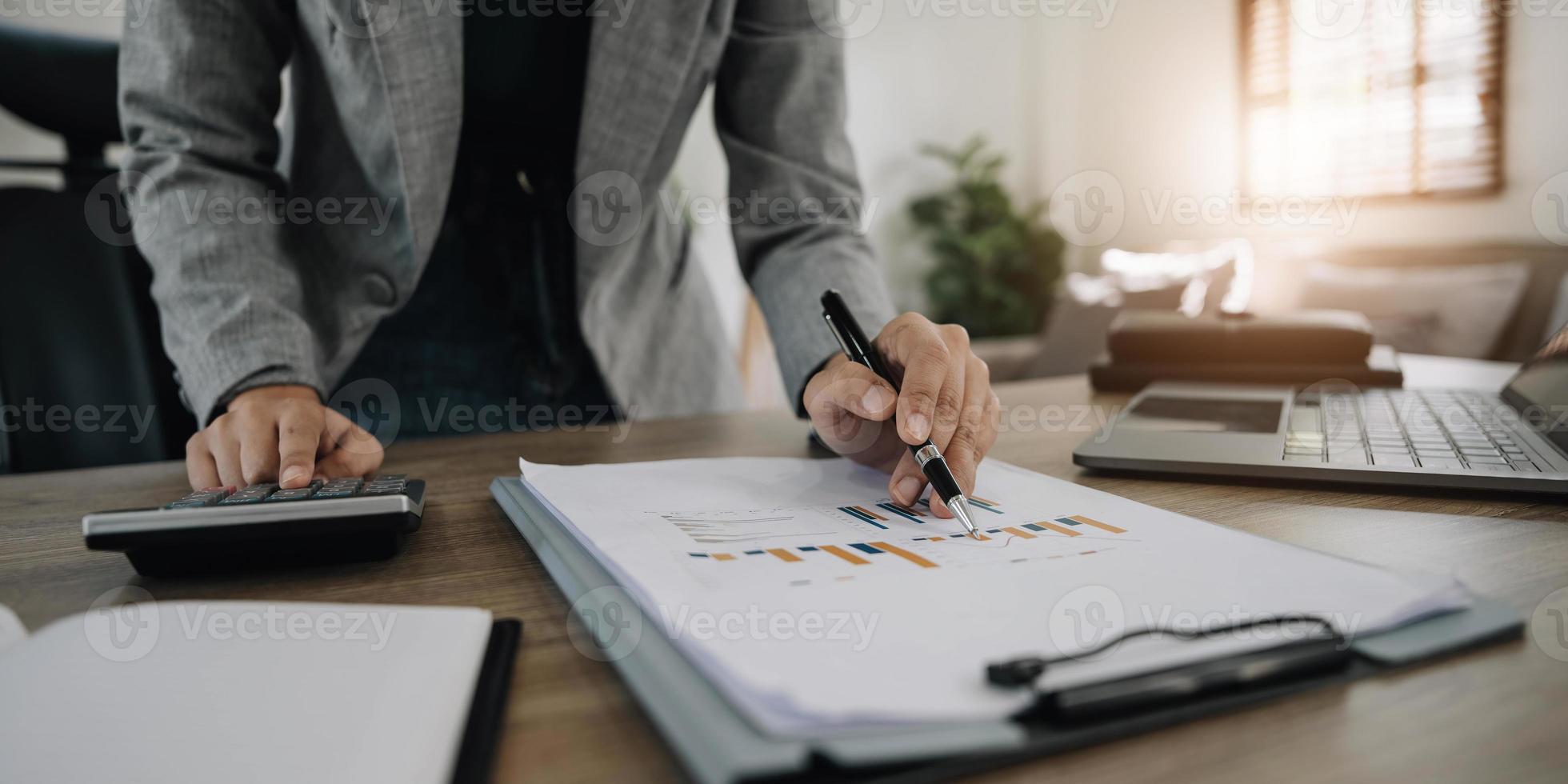 Close up Business woman using calculator and laptop for do math finance on wooden desk in office and business working background, tax, accounting, statistics and analytic research concept photo