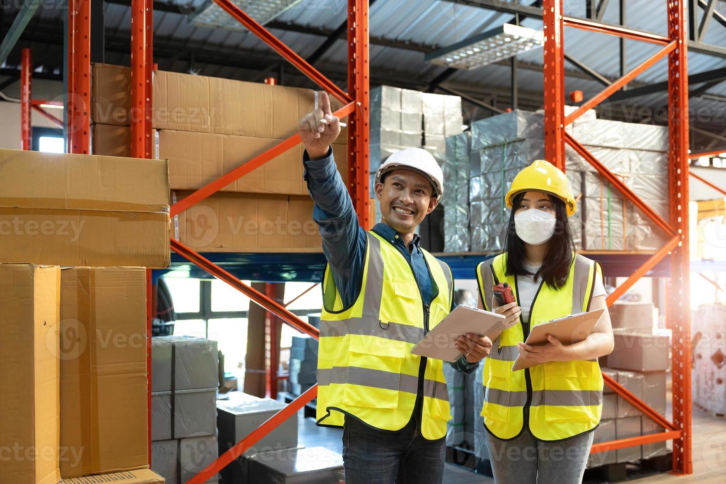 Professional adult Asian male warehouse manager and female worker are working together, checking their inventory in the warehouse or storehouse. photo