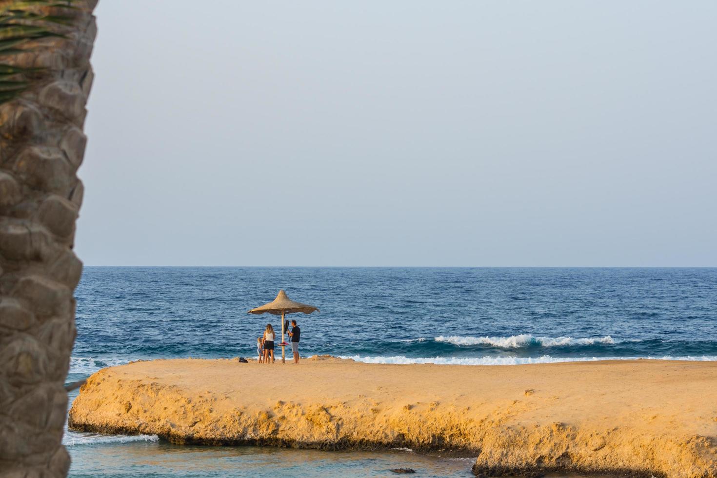 family under a single beach umbrella on a bay at the sea photo