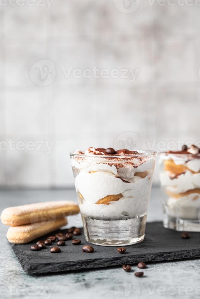 postre tradicional italiano tiramisú, fondo de piedra. Porción de postre con sabor a café a base de savoiardi y mascarpone decorado con cacao. foto