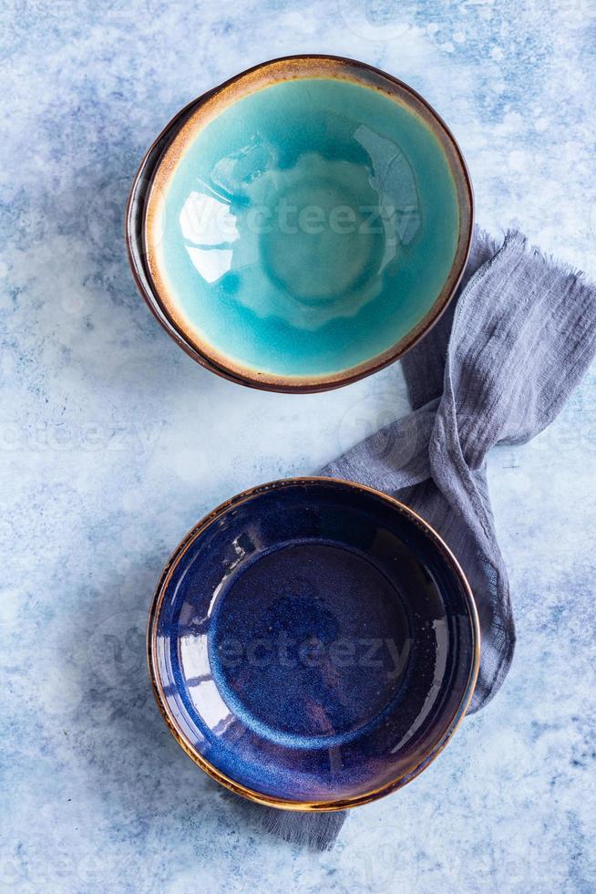 Set of empty craft marble plates and kitchen towel, blue concrete background. Ceramic tableware, beautiful arrangement. Top view. photo