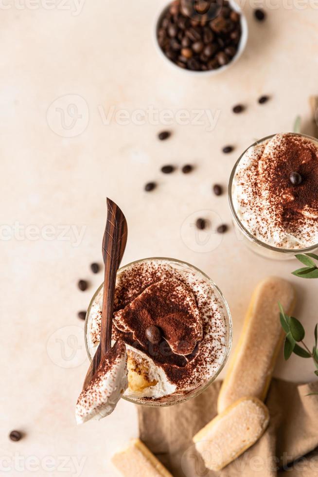 Traditional Italian dessert tiramisu, stone background. Coffee flavored portion dessert made of savoiardi and mascarpone decorated with cocoa. photo