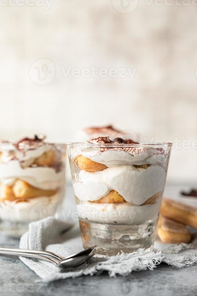 Traditional Italian dessert tiramisu, stone background. Coffee flavored portion dessert made of savoiardi and mascarpone decorated with cocoa. photo