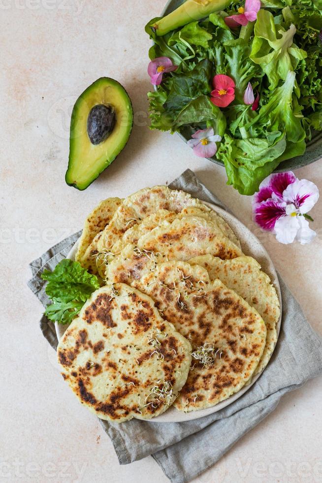 Homemade chapati or roti flatbread with green salad mix, avocado and sprouts, concrete background. Freshly baked Indian flatbread. photo