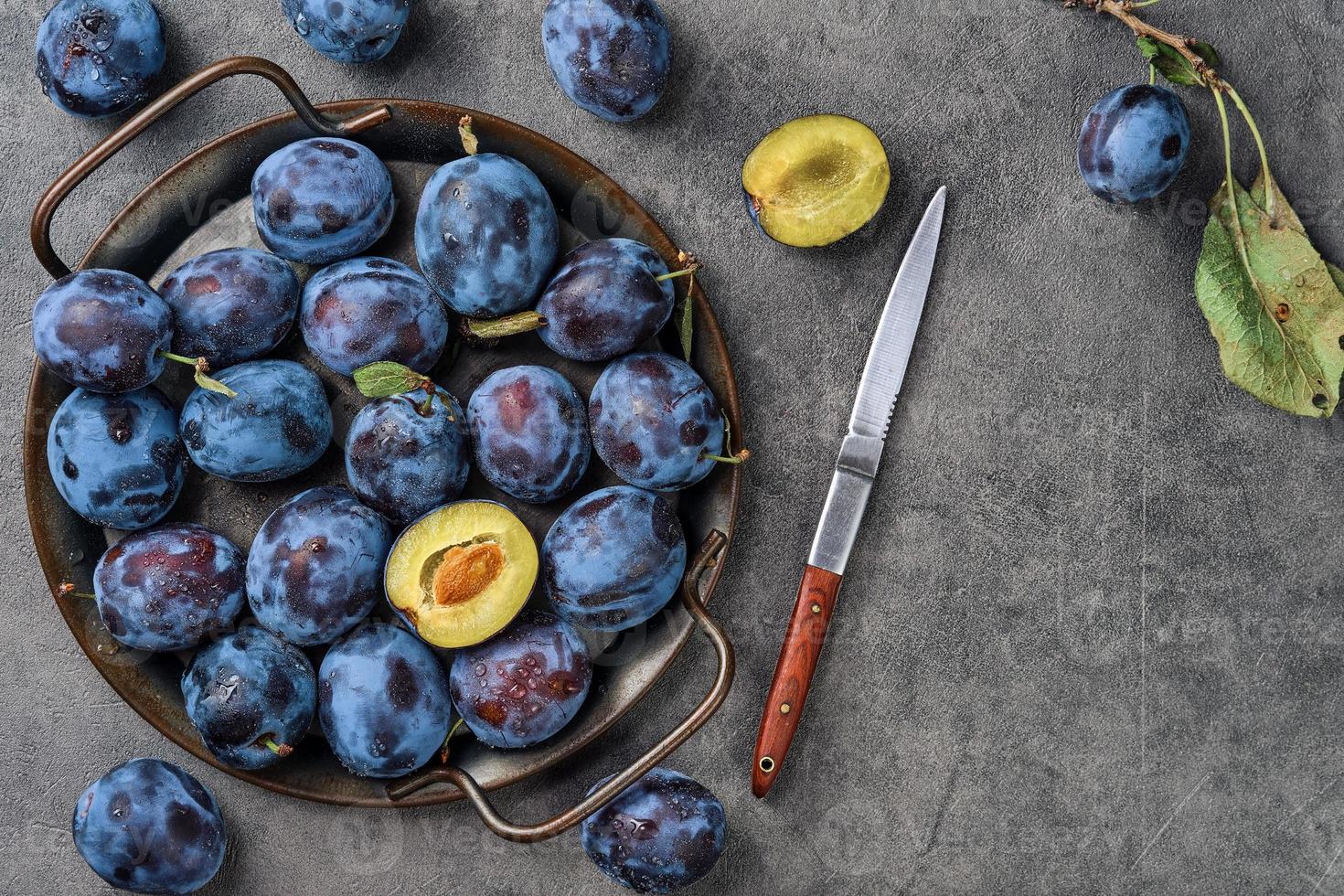 ciruelas en gotas de agua en un plato de metal sobre un fondo gris. vista superior con espacio de copia. hermosas ciruelas pasas maduras, cosecha de frutas en otoño, productos ecológicos de la granja foto