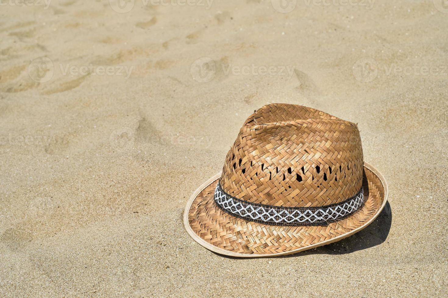 Men's straw beach hat on the sand at the beach, close-up, copy space for text. A beautiful sunny day. Vacation, summer concept photo
