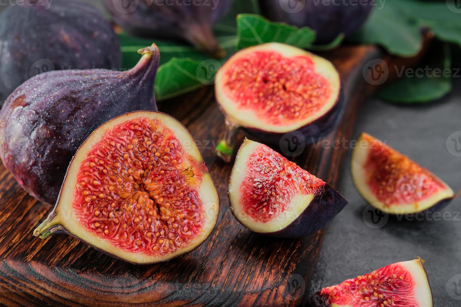 Figs cut into slices on a wooden cutting board close-up, selective focus. Horizontal frame seasonal ripe fig fruits, mediterranean diet, idea for advertising photo