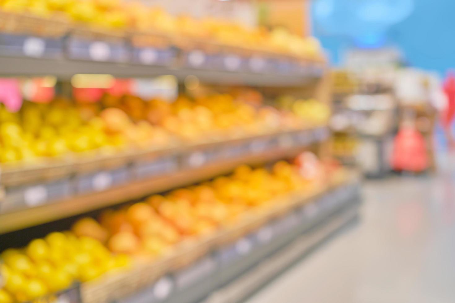 fondo borroso del interior de la tienda con filas de frutas frescas, papel tapiz desenfocado para oficina o supermercado con efecto bokeh. fondo con espacio libre para texto, idea para diseño de postal o sitio web foto