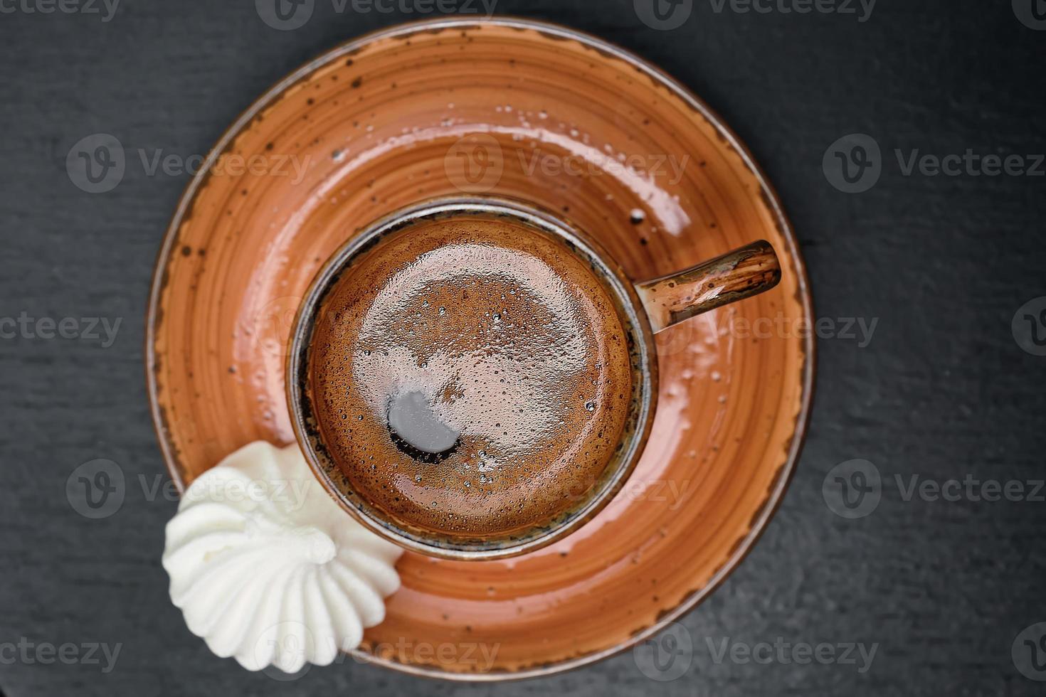 una taza con café turco fuerte sobre una mesa vieja negra, al lado del bizet, vista superior. foto