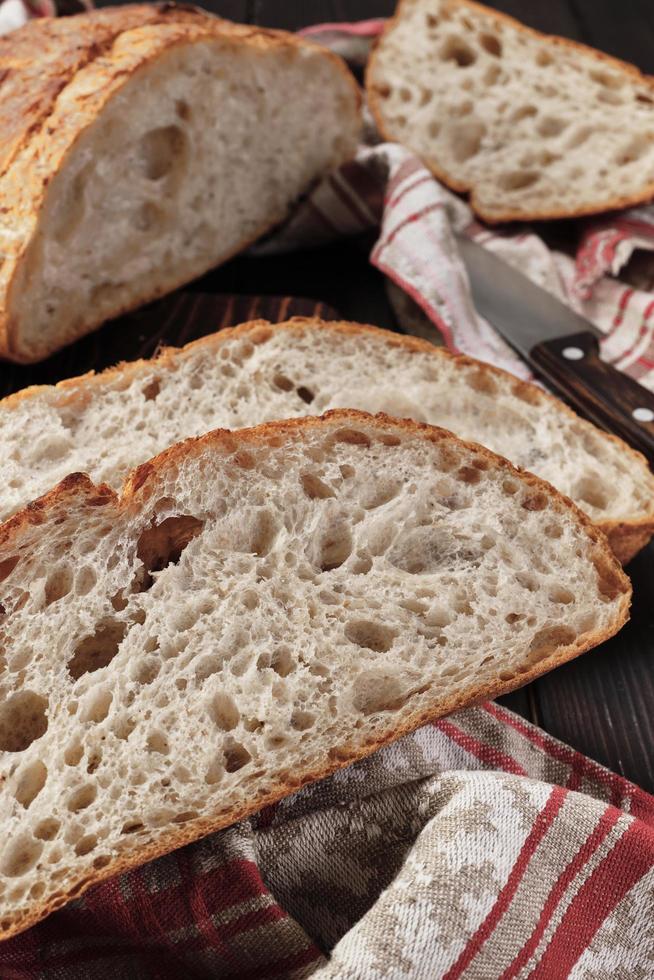 Close-up of pieces of rustic bread on a cotton towel. Homemade whole grain bread, layout on the table, vertical frame photo