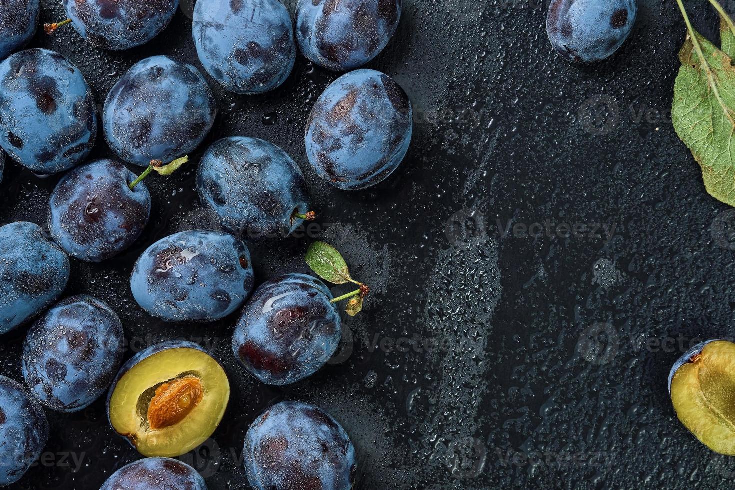 ciruelas en gotas de agua sobre el fondo de un tablero de piedra negra. vista superior con espacio de copia. hermosas ciruelas pasas maduras, cosecha de frutas en otoño, productos ecológicos de la granja foto