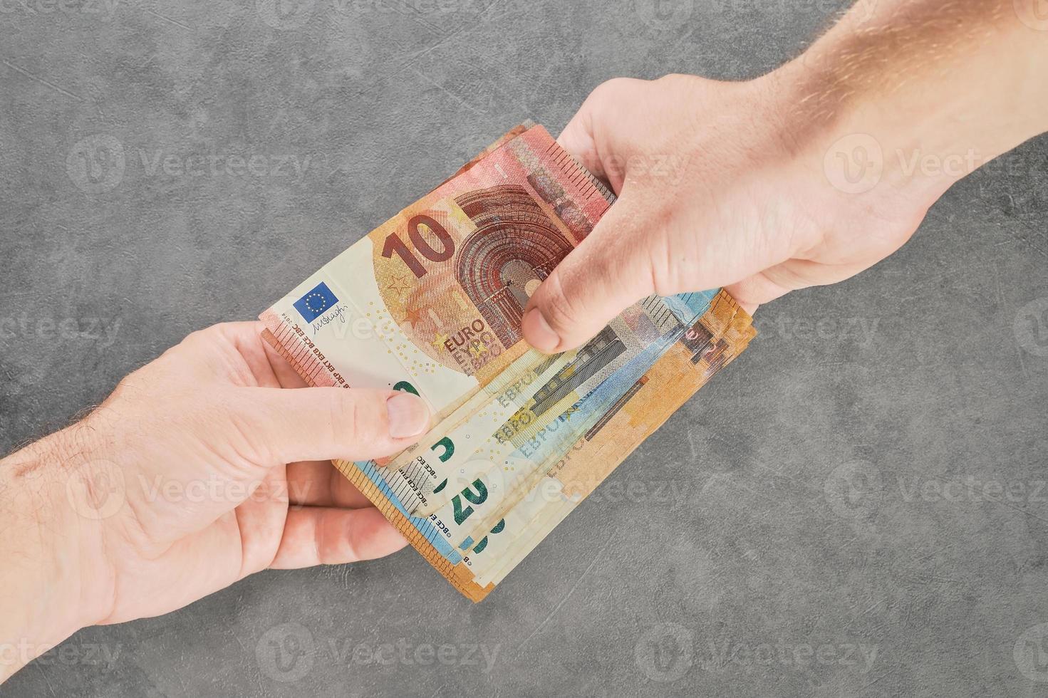 Close-up of two hands of people exchanging euro banknotes of different denominations for buying and selling, paying or taxing a debt, borrowing funds. Top view high quality photo, money loan photo