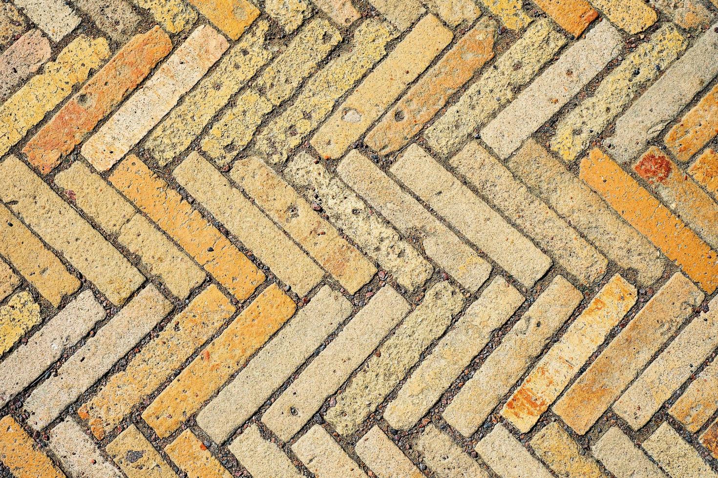 Pattern with rectangular yellow brick tiles in the form of a herringbone. Diagonal texture, abstract background of old brick ceramic cobblestone top view. Idea for easy desk wallpaper photo