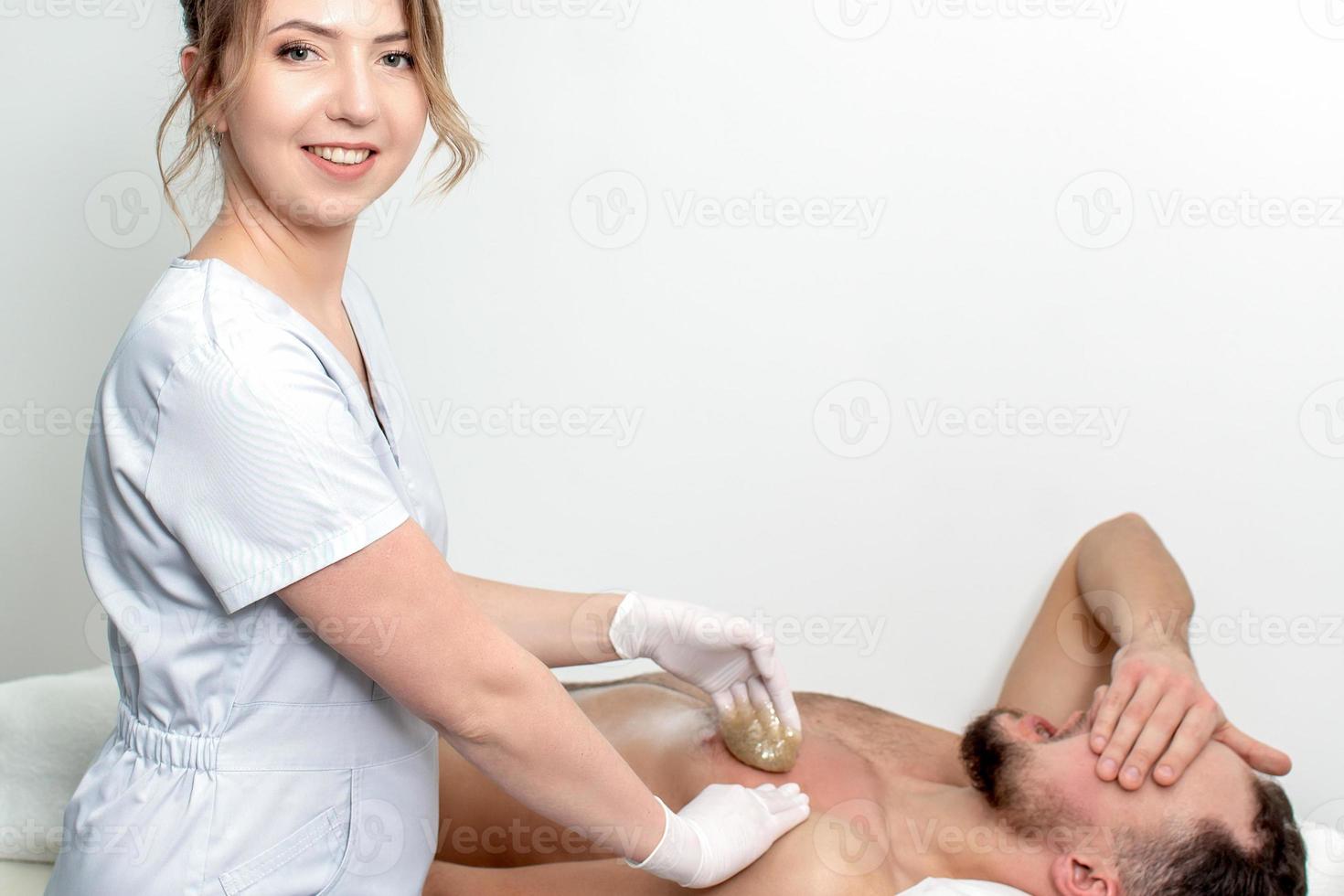 Young man receiving waxing chest photo