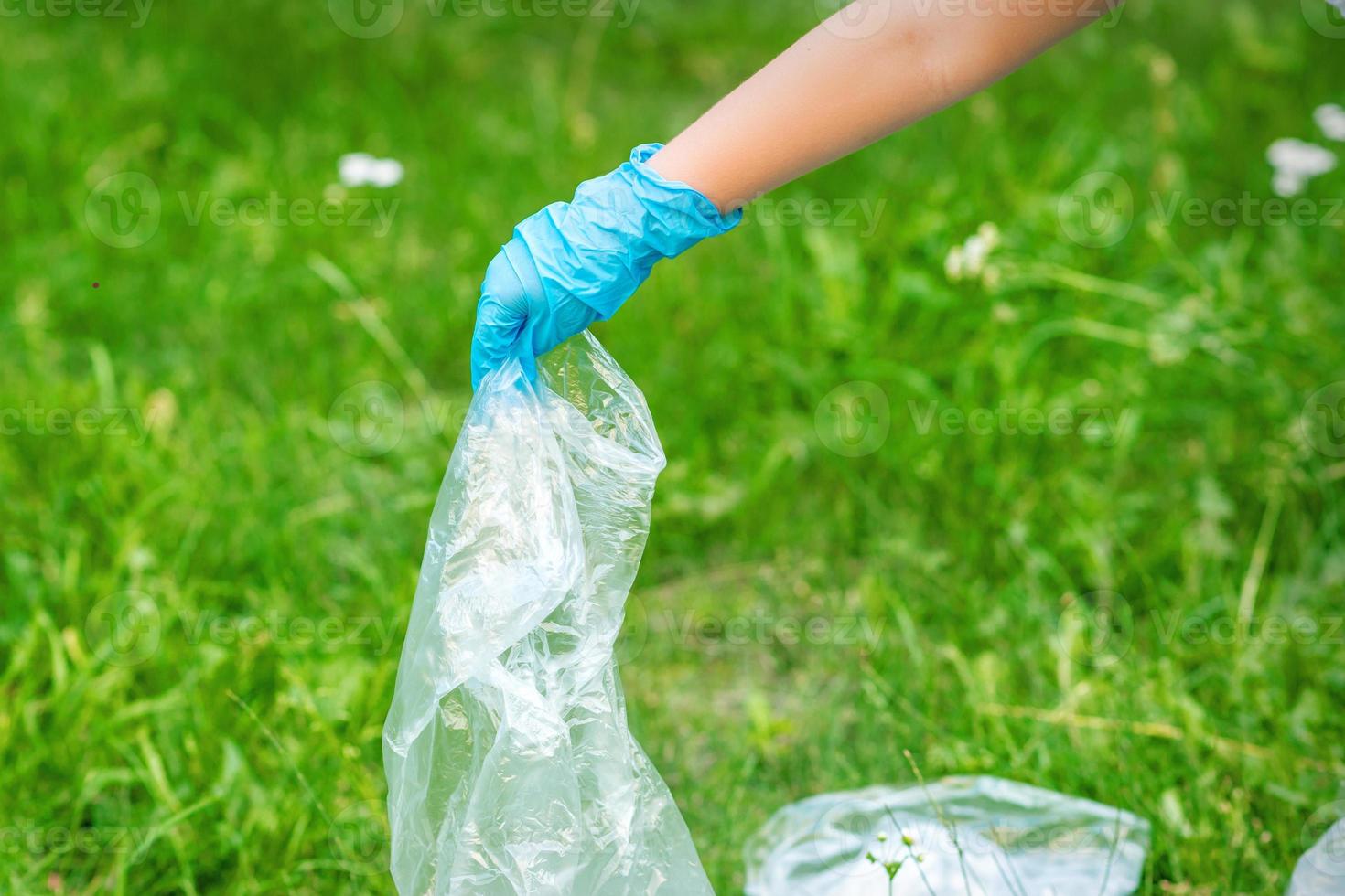 Hand of child cleans the park from plastic debris photo