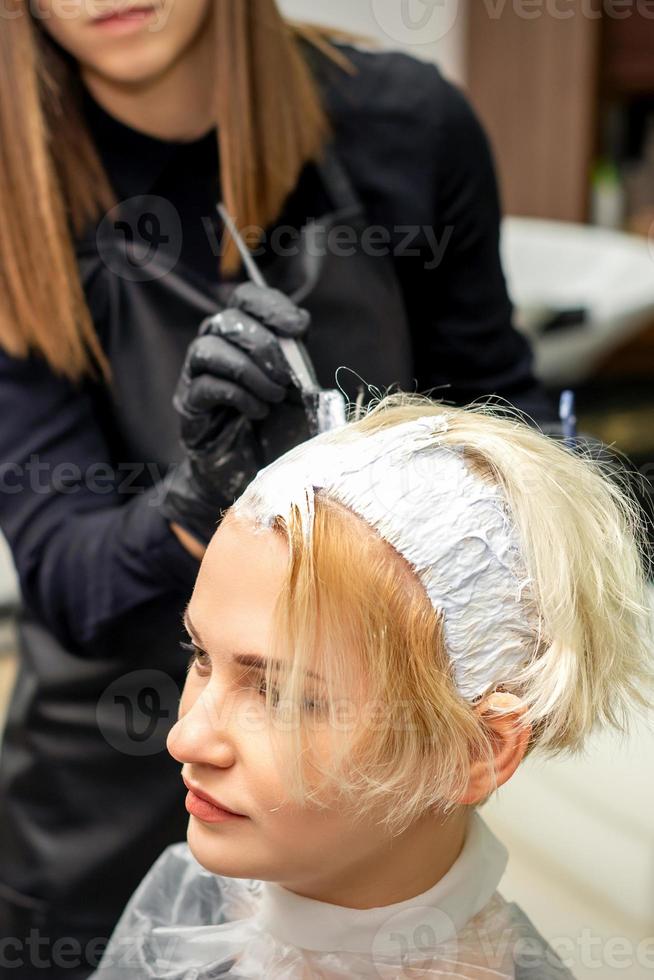 estilista aplica tinte blanco al cabello foto