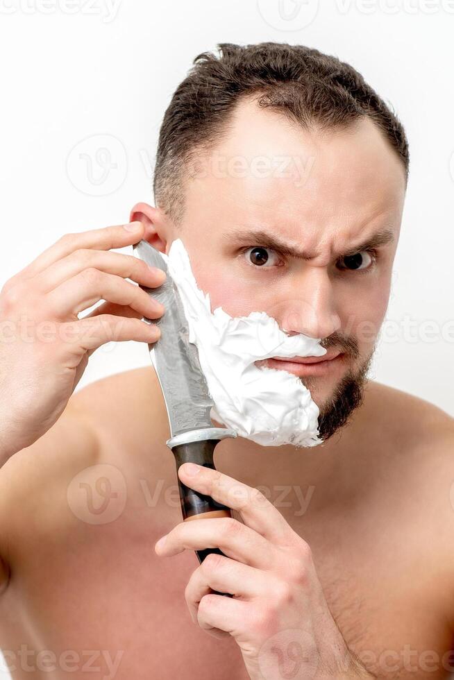 hombre afeitándose la barba con un cuchillo foto